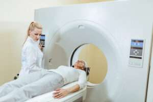 Das Bild zeigt eine Frau die in einen Hirnscanner fMRT gelegt wird. Traumatherapie beginnt im Gehirn